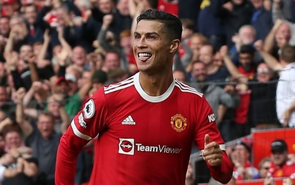 Jogador Cristiano Ronaldo vestindo camisa tradicional do Manchester United, enquanto comemora gol feito em partida