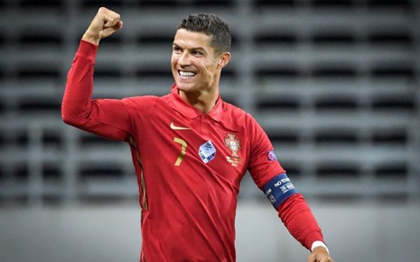 Cristiano Ronaldo com a camisa vermelha de Portugal, vibrando e acenando para a torcida após um gol