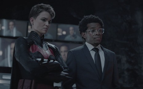 Ruby Rose e Camrus Johnson na primeira temporada de Batwoman; ela está com o traje da heroína, e ele tem expressão de desdém