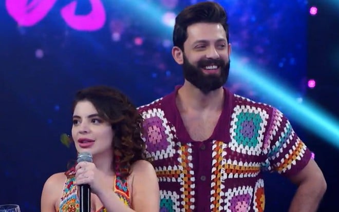 A comediante Gkay ao lado de seu professor na Dança dos Famosos, no palco do Domingão com Huck, ela séria e ele sorrindo