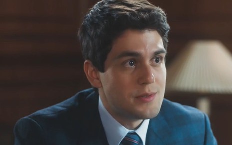 O ator Daniel Rangel com expressão séria em cena de Amor Perfeito, de terno e gravata