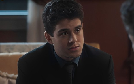 Em cena de Amor Perfeito, Daniel Rangel usa roupa preta e está falando com alguém