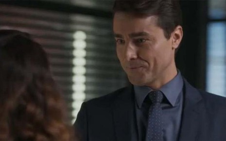 De terno e gravata, Ricardo Pereira fala com Taís Araujo (de costas) com expressão de deboche em cena de Cara e Coragem