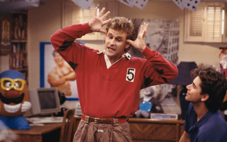 Dave Coulier interpretando tio Joey. Na imagem, ele está de blusa vermelha e fazendo uma careta.