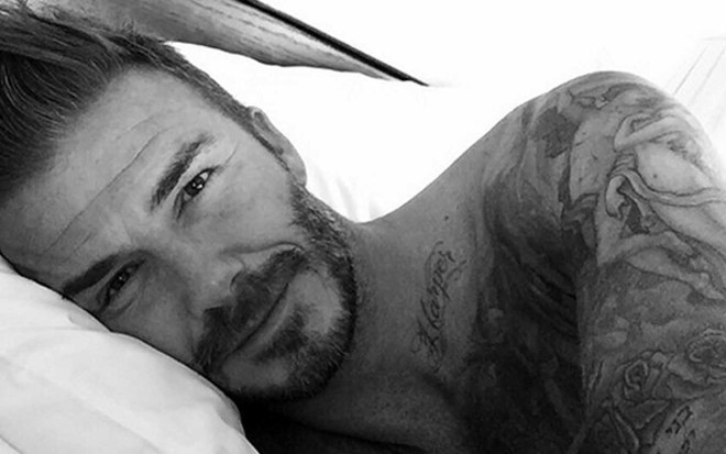O jogado David Beckham em uma foto preto-e-branco deitado em uma cama com a cabeça apoiada em um travesseiro