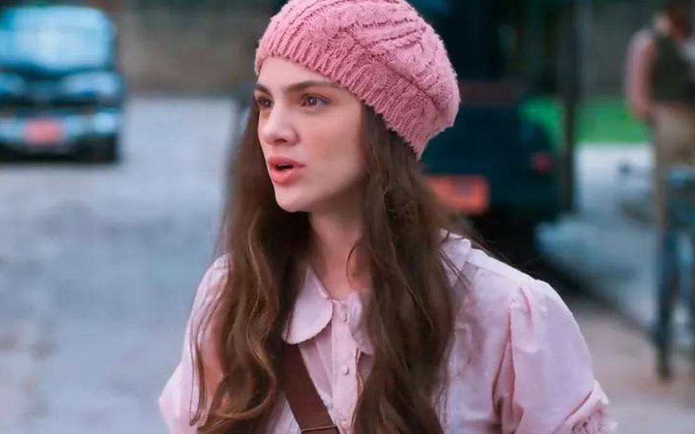 Debora Ozório usa uma touca rosa e está com expressão séria em cena como Olívia na novela Além da Ilusão