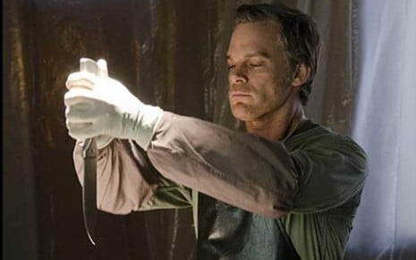 Michael C. Hall segura uma faca usando um par de luvas em cena da sétima temporada de Dexter