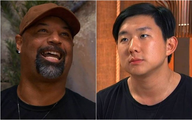 Dinei usa boné marrom, sorri e veste camiseta preta; Pyong olha para cima, está sentado e veste camiseta preta