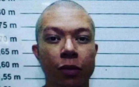 DJ Ivis de cabelo raspado e expressão séria, em foto de registro na prisão