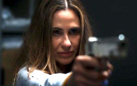 Dominique (Guilhermina Guinle) aponta uma arma para frente em cena de Salve-se Quem Puder