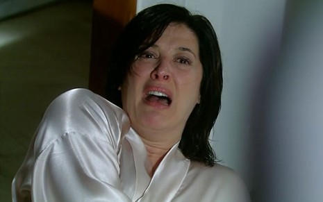 A atriz Claudia Raia como Donatela em A Favorita; ela está de cabelo molhado, caída no chão e olhando para cima com cara de horrorizada e prestes a chorar