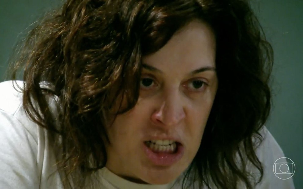 A atriz Claudia Raia como Donatela em A Favorita; descabelada, ela está olhando para a frente com cara de brava enquanto range os dentes