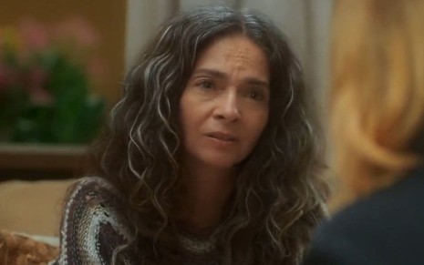 Claudia Ohana com expressão séria em cena como Dora na novela Vai na Fé