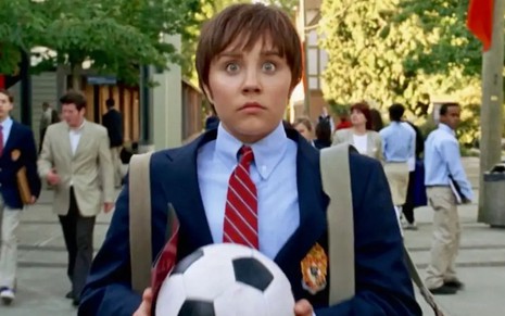 Com peruca masculina e terno, Amanda Bynes segura uma bola de futebol e tem expressão de choque no filme Ela É o Cara (2006)