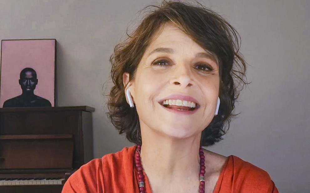 Drica Moraes está com fone de ouvido e foi fotografada pelo computador