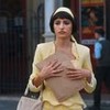 Personagem Iolanda de roupa amarela com envelope de papel pardo em mãos