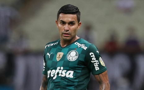 Dudu em campo pelo Palmeiras. Ele usa uma camisa verde e vê uma bola chegar perto.