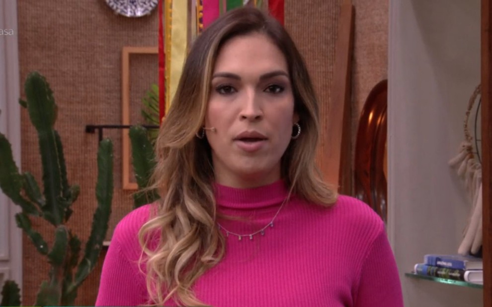 A apresentadora Talitha Morete de blusa rosa de manga comprida, expressão séria, durante o É de Casa