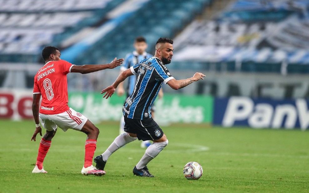 Edenilson, do Internacional e usando uma camisa vermelha, toma um drible de Maicon, do Grêmio, que usa uma camisa azul na Arena do Grêmio