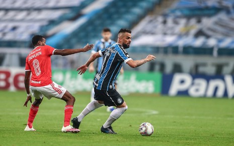 Edenilson, do Internacional e usando uma camisa vermelha, toma um drible de Maicon, do Grêmio, que usa uma camisa azul na Arena do Grêmio