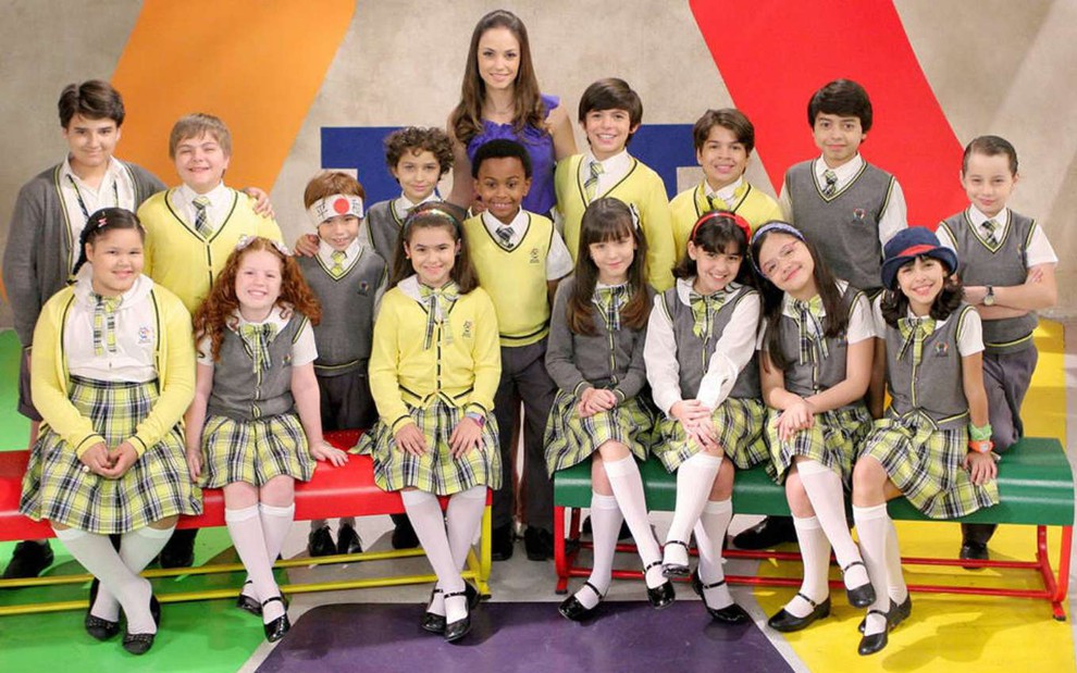Elenco de Carrossel (2012) em foto de divulgação; atores mirins vestidos com uniformes escolares, professora no centro