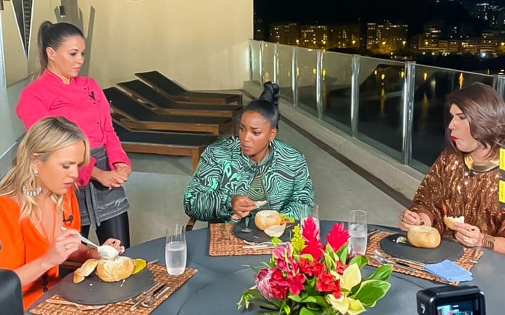 Eliana, chef de cozinha, Iza e Narcisa sentadas à mesa para fazer uma refeição esquisita na cobertura da apresentadora