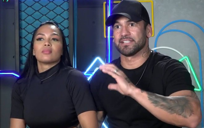 Foto de Eliza sentada ao lado de Hadballa; os dois vestem camisetas pretas