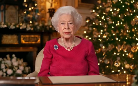 Rainha Elizabeth 2ª sentada em frente a uma árvore de natal