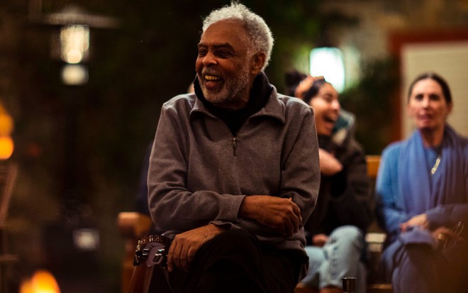 Gilberto Gil sorri em cena noturna de Em Casa com os Gil, durante festa em sua casa