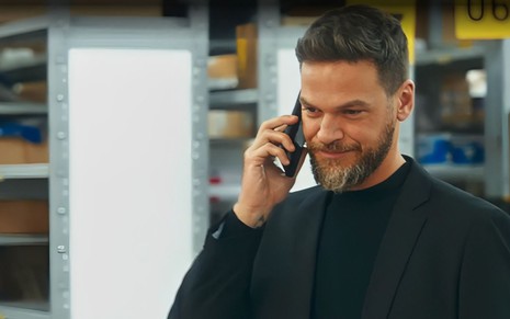 Em cena de Vai na Fé, Emilio Dantas usa blusa preta está falando com alguém ao telefone