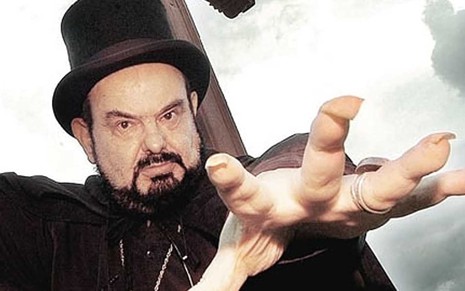 O ator José Mojica Maris como Zé do Caixão estende a mão direita com longas e sujas unhas em cena do filme Encarnação do Demônio