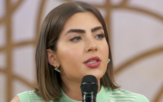 Jade Picon durante participação no Encontro desta sexta (2), com microfone na frente da boca, expressão séria