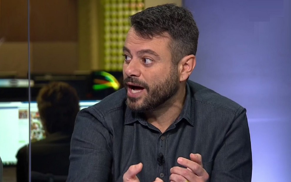 Eric Faria no Redação SporTV com uma camisa azul e rosto firme em um debate sobe futebol