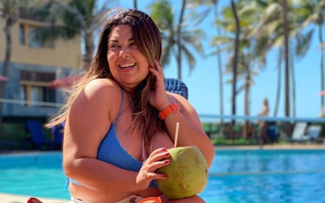 Fabiana Karla sorrindo de biquíni e com uma água de coco