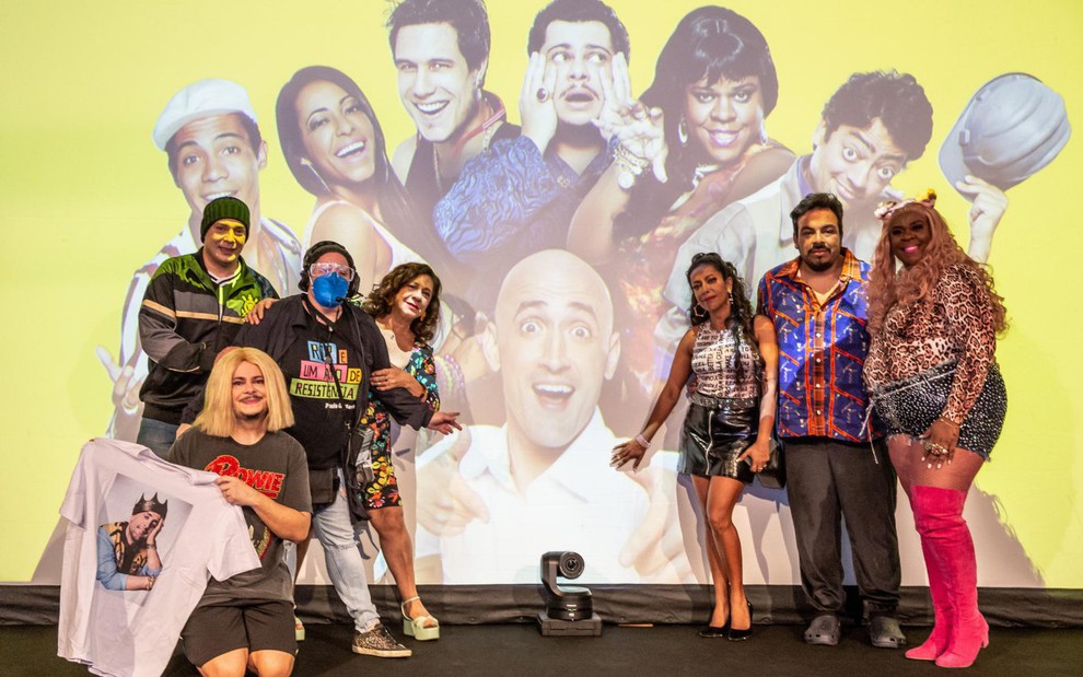 Imagem do elenco do Vai que Cola na frente de um telão com a imagem de Paulo Gustavo