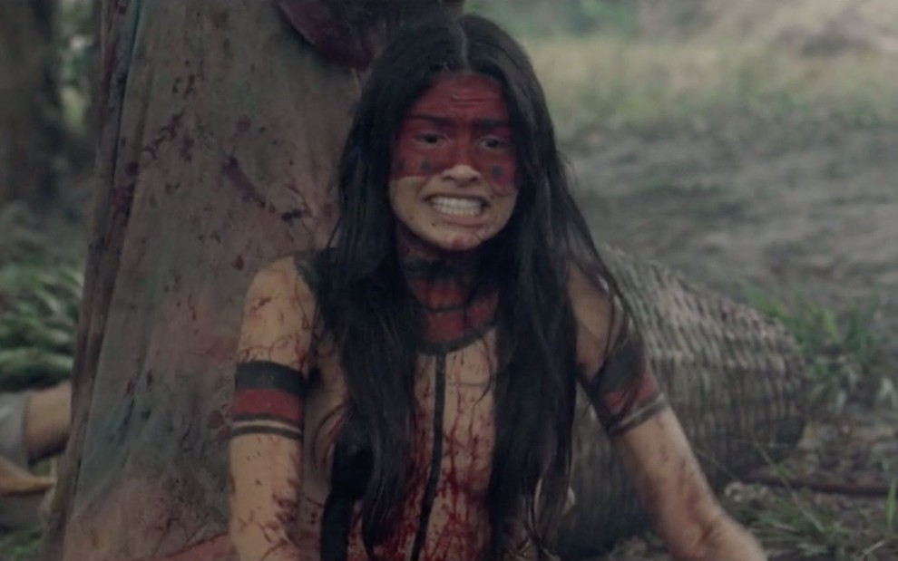 A atriz Allana Lopes caracterizada como a personagem índia Aiyra no filme O Cemitério das Almas Perdidas; ela aparece pintada de tinta vermelha, suja de sangue e gritando de desespero