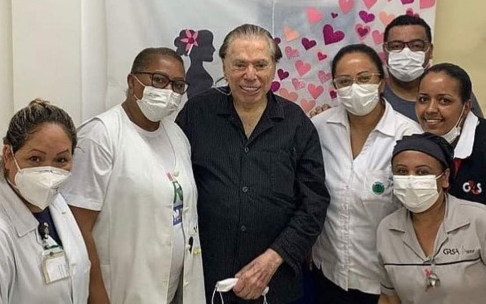 O apresentador Silvio Santos sorri em foto ao lado de equipe de enfermeiros após tomar terceira dose contra a Covid-19