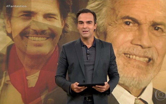 O apresentador Tadeu Schmidt no palco do Fantástico no domingo (15) na Globo; no telão atrás dele, imagens do ator Tarcísio Meira