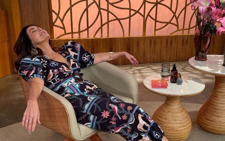 Fátima Bernardes veste macacão estampado e deita em cadeira localizada no seu estúdio da Globo
