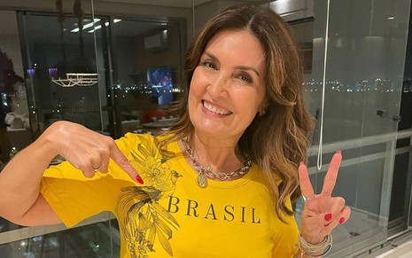 Fátima Bernardes sorri e veste camisa com as cores do Brasil