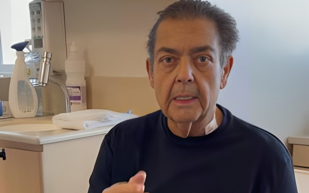 O apresentador Fausto Silva com expressão séria, olhando para câmera, em vídeo gravado em quarto de hospital
