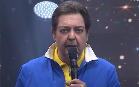 Fausto Silva apresenta o Faustão na Band de blusa azul e camisa amarela