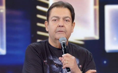 Fausto Silva usa camiseta e segura o microfone enquanto apresenta edição do Domingão do Faustão em abril