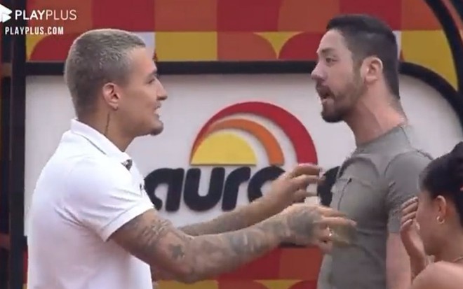 MC Gui veste camiseta branca e está com a mão próxima ao rosto de Rico; Rico veste camiseta cinza e está com a boca aberta