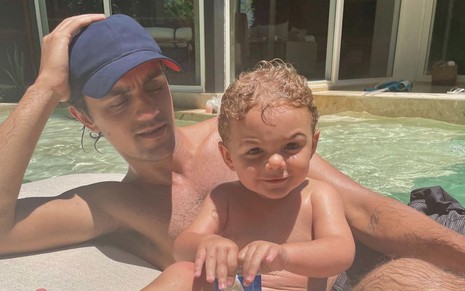 Felipe Simas e o filho caçula Vicente na borda de uma piscina em dia de sol