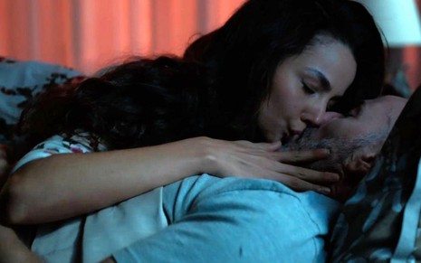 Cecília (Fernanda Marques) está deitada em cima de Breno (Marco Ricca) e o beija em cena da novela Um Lugar ao Sol