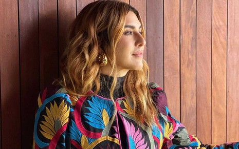 A atriz Fernanda Paes Leme em foto publicada no Instagram, ela está de perfil, com roupa colorida, em frente a painel de ripas de madeira