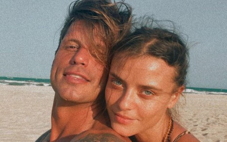 Fernando Fernandes e a namorada, Laís Oliveira, abraçados em meio à praia