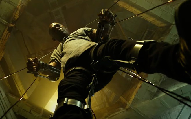Marcus Banks (Samuel L. Jackson) visto de baixo para cima com braços e pernas presos por hastes metálicas em cena do filme Espiral: O Legado de Jogos Mortais