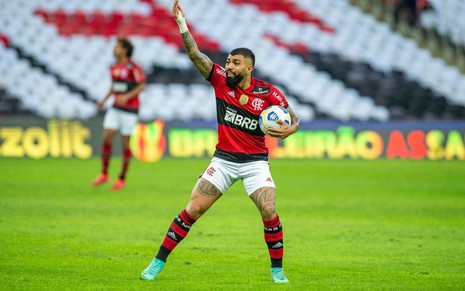Com uniforme tradicional do Flamengo, Gabigol segura a bola e levanta o braço em jogo no Maracanã